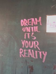 graffiti written on the side of a building reads dream until it's your reality