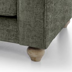 a close up view of the back end of a green couch with wood legs and arms