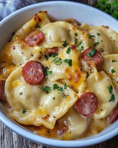 a white bowl filled with pasta covered in cheese and pepperoni toppings on top of a wooden table