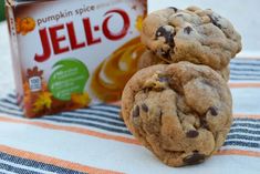 two chocolate chip cookies sitting next to a box of jello on a tablecloth