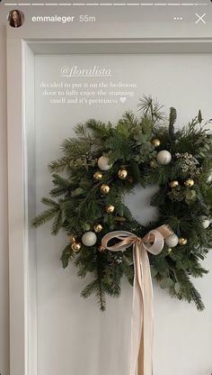 a christmas wreath is hanging on the wall in front of a door with a ribbon