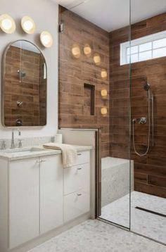 a large bathroom with wooden walls and white fixtures, along with a walk in shower