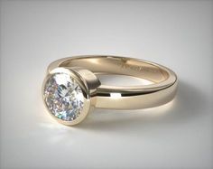 a gold engagement ring with a round diamond in the center, on a white background