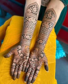 two hands with henna tattoos on them, one is showing the intricate pattern and the other has an elaborate design