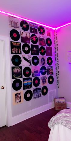 a bed room with a neatly made bed and lots of vinyl records on the wall