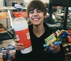 a boy holding up a cup and some candy