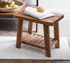 a wooden stool with a white towel and some bread in a basket on the side