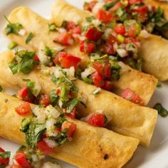 three tortillas on a white plate topped with tomatoes and cilantro sauce