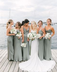 a group of women standing next to each other on a wooden dock near the water