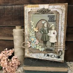 an altered picture frame sitting on top of two books next to some flowers and twine