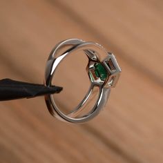 It is a lab emerald ring. The main stone is 7mm*7mm round cut, weight about 1.3 carats. The basic metal is sterling silver and plated with rhodium. To change the metal to a solid gold (white/rose) or platinum is also available, please ask for a quotation if you want. You can also go to my shop Home for more elegant rings: https://www.etsy.com/shop/godjewelry?ref=hdr_shop_menu More lab emerald rings: https://www.etsy.com/shop/godjewelry?ref=seller-platform-mcnav&section_id=20709240 Customizat 14k White Gold Emerald Cut Halo Ring, Fine Jewelry Emerald Solitaire Ring In Round Cut, Elegant Emerald Ring With Bezel Setting, Emerald Cut Gemstone Halo Ring In White Gold, Formal White Gold Emerald Ring With Round Stone, Round Cut Emerald Diamond Ring, Emerald Cut Moissanite Jewelry With Halo Design, Sterling Silver Emerald-cut Emerald Ring For Promise, Cubic Zirconia Emerald Cut Halo Promise Ring