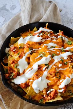 a skillet filled with nachos covered in cheese and sauce