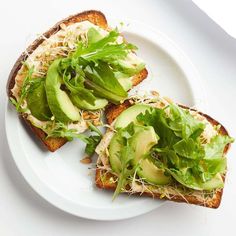 two pieces of bread with lettuce and avocado on it sitting on a plate