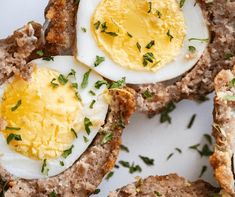 an egg is on top of some meat patties with parsley sprinkled on them