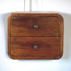 a wooden cabinet with two drawers hanging on the wall