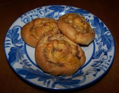 three small pastries on a blue and white plate with floral design pattern, sitting on a wooden table