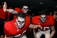 two football players with their faces painted in white and red are posing for the camera