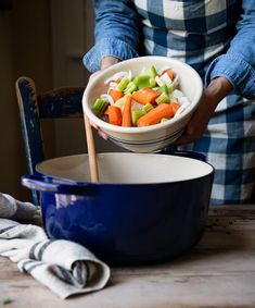 a person holding a bowl with vegetables in it