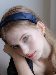 a girl with blue eyes and a bow in her hair is posing for the camera