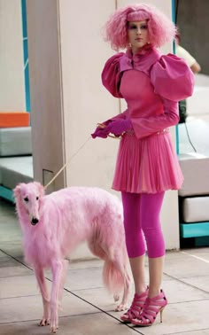 a woman in pink is standing next to a dog