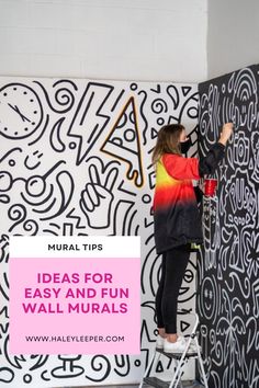 a woman painting a wall with black and white graffiti