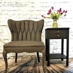 a chair next to a side table with flowers in a vase on top of it