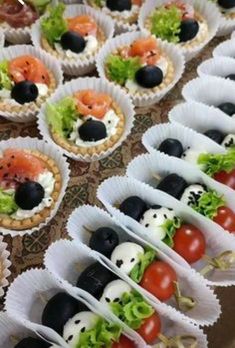 many different types of food are arranged in small trays on a table with paper wrappers