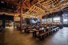 an empty restaurant with wooden benches and lights hanging from the ceiling over it's tables