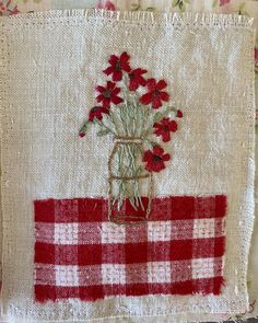 a red and white checkered table cloth with flowers in a mason jar on it