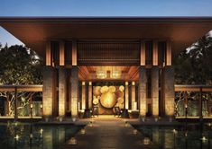 the entrance to a resort at night with candles lit up on the walkway and lights in the water