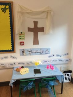 a blue table topped with two green chairs next to a white wall covered in pictures