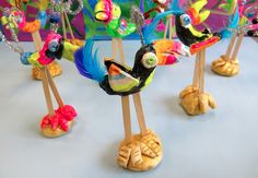 colorfully painted birds are standing on wooden sticks