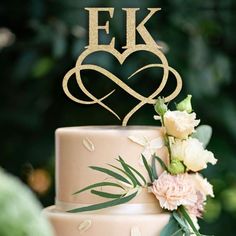 a wedding cake with the initials f k and heart on top, surrounded by flowers