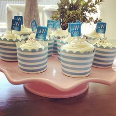 cupcakes with blue and white striped frosting are on a pink platter