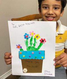 a young boy holding up a card with flowers in it