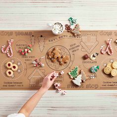 a person reaching for some cookies on a board with christmas decorations around it and the word merry written in large letters