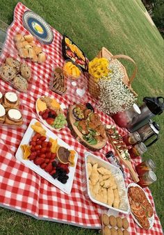 a picnic blanket with food on it in the grass