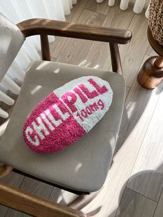 a pink and white pillow sitting on top of a chair