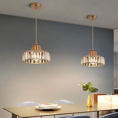 a dining room table with blue chairs and two pendant lights hanging from it's ceiling