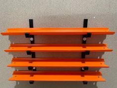 an orange shelf with four black brackets on it