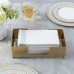 a table topped with plates and silverware next to a vase filled with white flowers