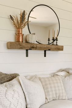 a living room with a couch, mirror and candles on the shelf over it's head