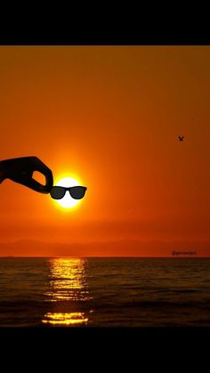 the sun is setting over the ocean with sunglasses on it