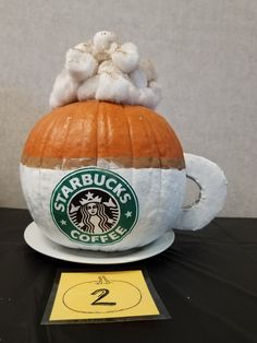 a starbucks pumpkin sitting on top of a coffee cup