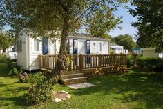 a mobile home sits in the grass next to a tree