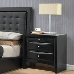 a bedroom with a bed, night stand and lamp on the side table next to it