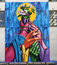 a painting on the side of a building with hands holding each other and flowers in their hands