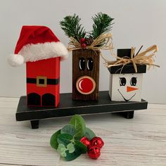 two christmas decorations sitting on top of a wooden shelf next to holly wreaths and ornaments