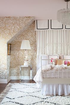 a white bed sitting under a chandelier next to a wall covered in curtains