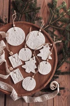 some ornaments are sitting on a wooden plate next to a ribbon and pine tree branches